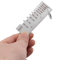 Hand holding a small metal gauge ruler on a white background
