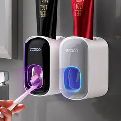 Two ecoco toothbrush holders with a hand holding a purple toothbrush against a gray background.