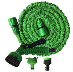 A green retractable garden hose with a flexible coiled body, shown with a detachable spray nozzle, a hose connector, and two small adapter pieces on a plain white background.