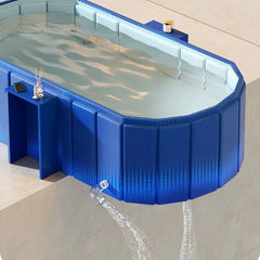 A blue modular outdoor plunge pool with water filled and a water spout in the foreground, shown on a light beige patio surface.