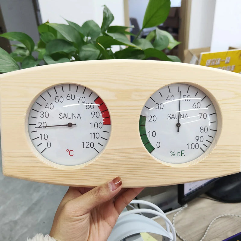 Wooden thermometer and humidity gauge held by a hand with plants in the background