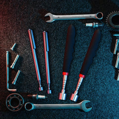 Collection of tools including wrenches, screwdrivers, and pliers on a dark textured surface.