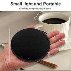 Black round device held in a hand with a cup of coffee in the background