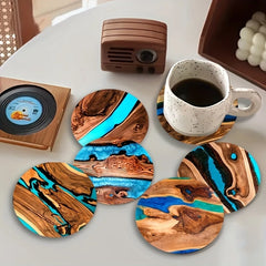Wooden coasters with blue and brown design on a table with a cup of coffee.