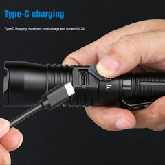 Black flashlight with Type-C charging cable being plugged in, on a black background.