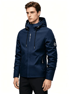 A man wearing a navy blue hooded jacket with black zippers and white logo details, paired with black pants, photographed against a plain white background.
