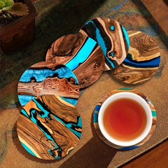Wooden coasters with blue and brown design on a woven surface with a cup of tea.