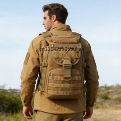 A man viewed from behind wearing a tan tactical backpack with multiple straps and a front zippered compartment, standing outdoors against a pale blue sky.