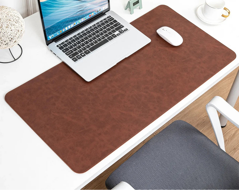 Laptop on a desk with a large brown mouse pad, mouse, and decorative items.