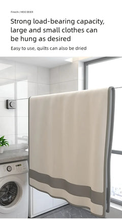 A beige and gray laundry towel or hanging cloth displayed in a bright laundry room with a washing machine, tiled walls, and a window. Text at the top describes strong load-bearing capacity and suitability for large and small clothes.