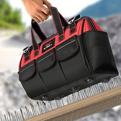 Black and red tool bag held by a hand with a blurred outdoor background
