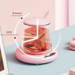 Pink electric tea maker with a clear glass container on a light blue surface.