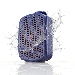 A blue waterproof speaker with a geometric honeycomb grille, shown with a dynamic water splash and droplets around it on a white background.