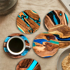 Wooden coasters with blue resin on a table with a cup of coffee.
