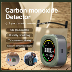 Carbon monoxide detector alarm shown on a wooden table with promotional text, including CO gas detection, humidity monitoring, temperature monitoring, and excess concentration alarm. The device is gray with a black display screen showing red, yellow, and green indicator rings.