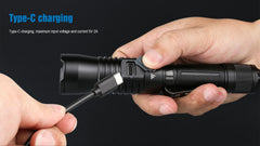 Person charging a black flashlight with a Type-C cable on a dark background