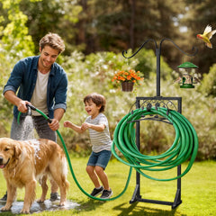 Man and child with a dog using a garden hose, with a garden hose stand and bird feeders in the background.