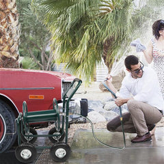 Man using a hose to wash a car with a woman watching, outdoors.