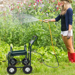 Person using a garden hose with a reel cart in a garden setting