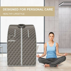 Person meditating in front of a gray Giantex sauna tent with a modern interior background.
