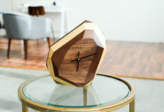Wooden clock with gold accents on a glass table in a room setting